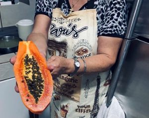 woman holding half of a fresh papaya 